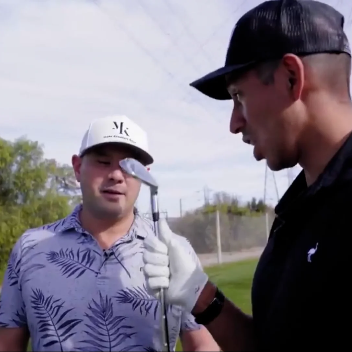 Two golfers on a course examining a golf club